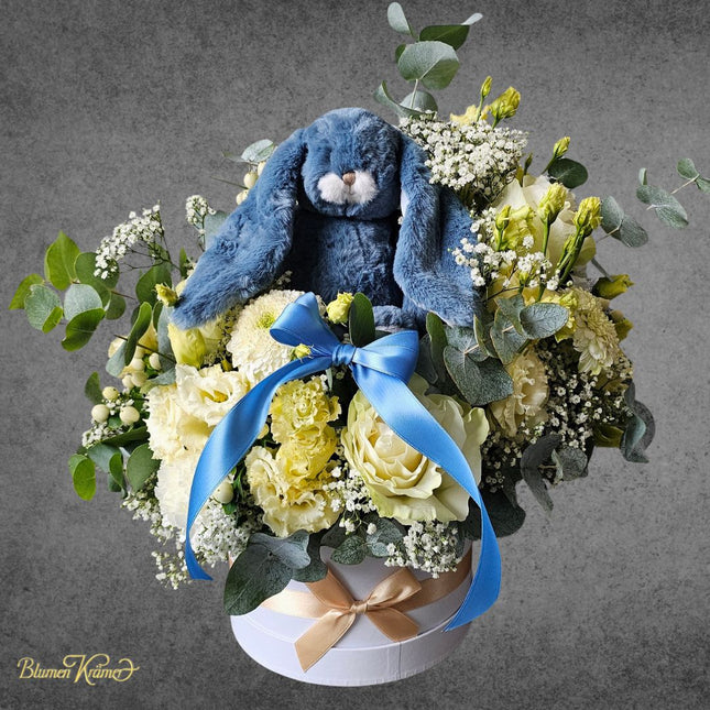 Liebevolle Blumenbox mit weissen Blumen und blauem Kuschelhasen als Baby Geschenk zur Geburt Zürich