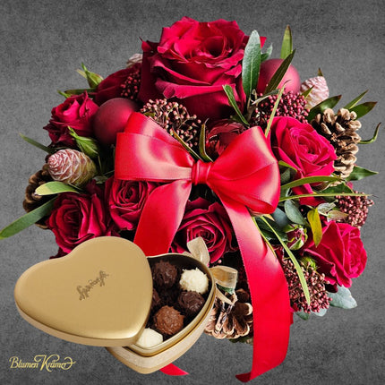 Weihnachtlicher Blumenkorb mit roten Rosen Zapfen und winterlichen Akzenten aus Zürich mit Sprüngli Schokolade