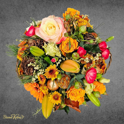 Winterlicher Blumenkorb in Orange und Rosa mit saisonalen Blüten und Zapfen liebevoll arrangiert aus Zürich
