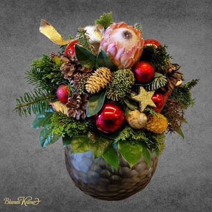 Blumenstrauss Winter Time mit Protea, Weihnachtskugeln und Zapfen aus Zürich bringt festliche Adventsstimmung und winterliche Eleganz