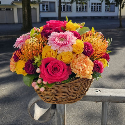 Farbenfroher Blumenkorb mit pinken und gelben Rosen, rosa Chrysanthemen, bordeauxfarbenen Blüten und saisonalen Blumen online bestellen Zürich