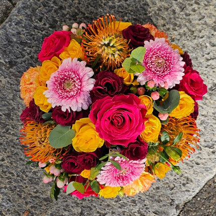 Farbenfroher Blumenkorb mit pinken und gelben Rosen, rosa Chrysanthemen, bordeauxfarbenen Blüten und saisonalen Blumen online kaufen Zürich
