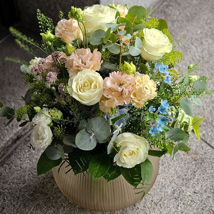Zarter Blumenstrauss mit cremefarbenen Rosen, apricotfarbenen Blüten und blauen Akzenten