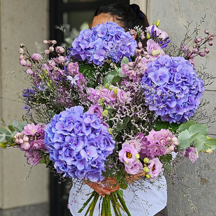 Lila Blumenstrauss mit violetten Hortensien, rosa Rittersporn, Lisianthus und Eukalyptus als Geschenk