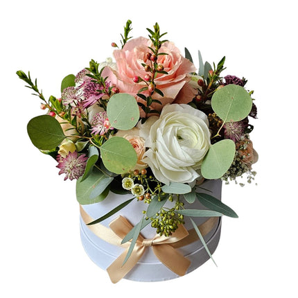 Elegante Blumenbox mit Rosen, Ranunkeln und Eukalyptus in Rosé- und Cremetönen in runder Geschenkbox mit Schleife