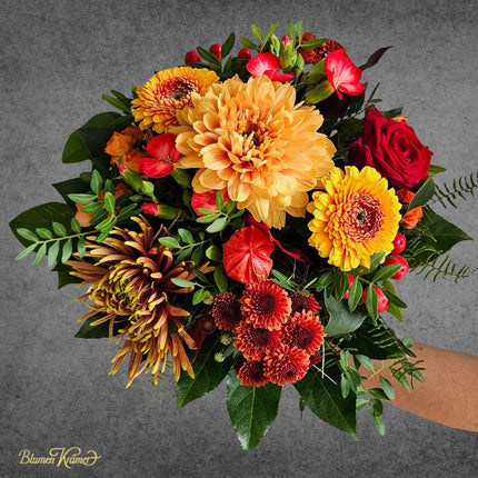 Herbststrauss mit leuchtend gelber Chrysantheme im Mittelpunkt und Blüten in Rot und Braun frisch geliefert vom Floristen in Zürich